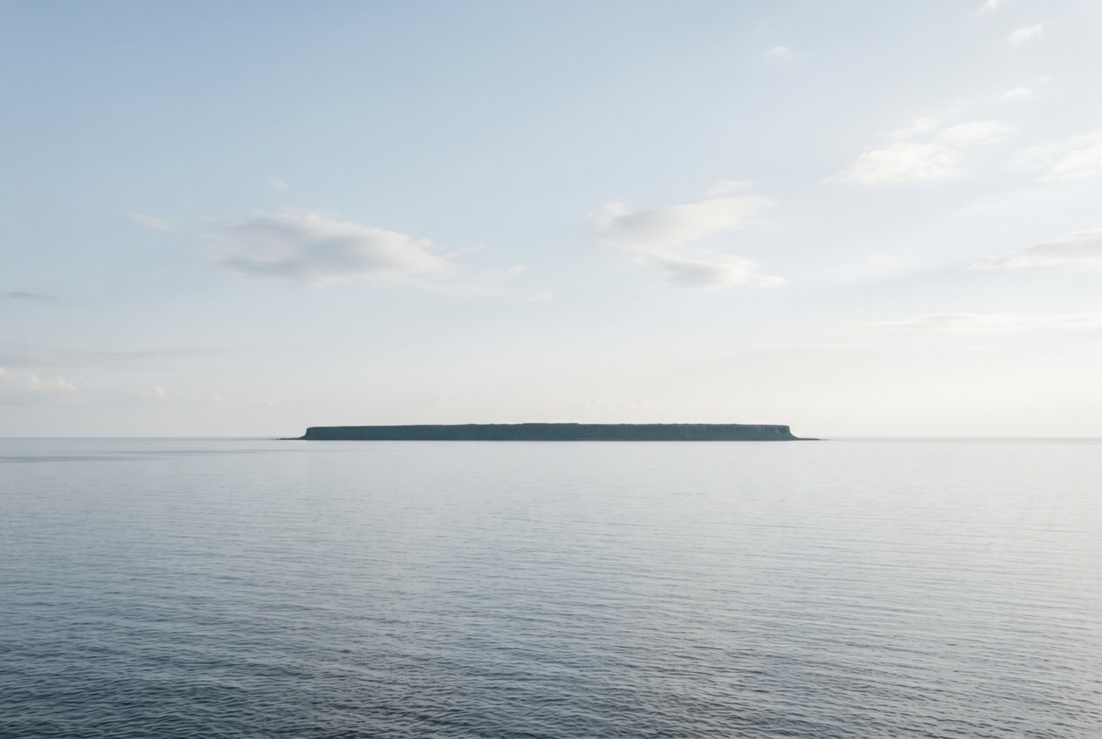 静かな海の上に浮かぶ、平らな島(イメージ画像)